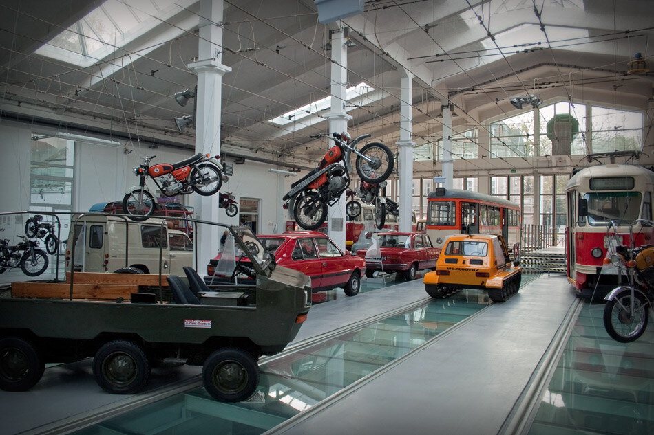 obraz przedstawia wnętrze muzeum Techniki i Komunikacji w Szczecinie; widoczne są pojazdy poprzednich dekad- tramwaje samochody i motory