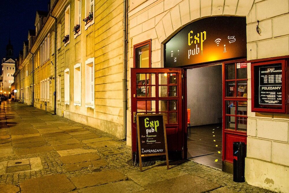 obrazek przedstawia wielkie drewniane oszklone drzwi, które jest wejściem do Exp Pubu w Szczecinie