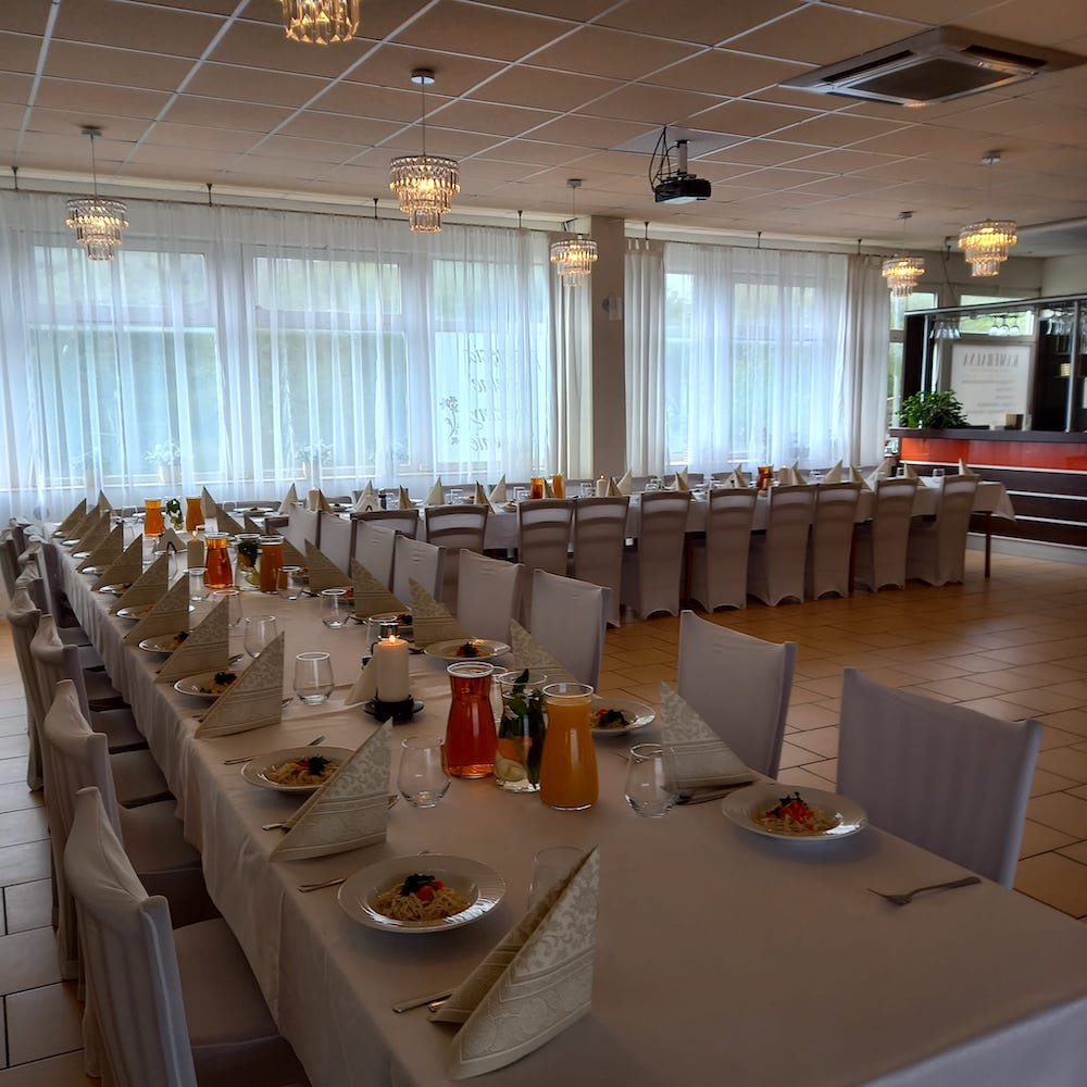 obraz przedstawia jasne wnętrze sali Kameralna ze Szczecina; stoły ustawione w kształcie litery "L"