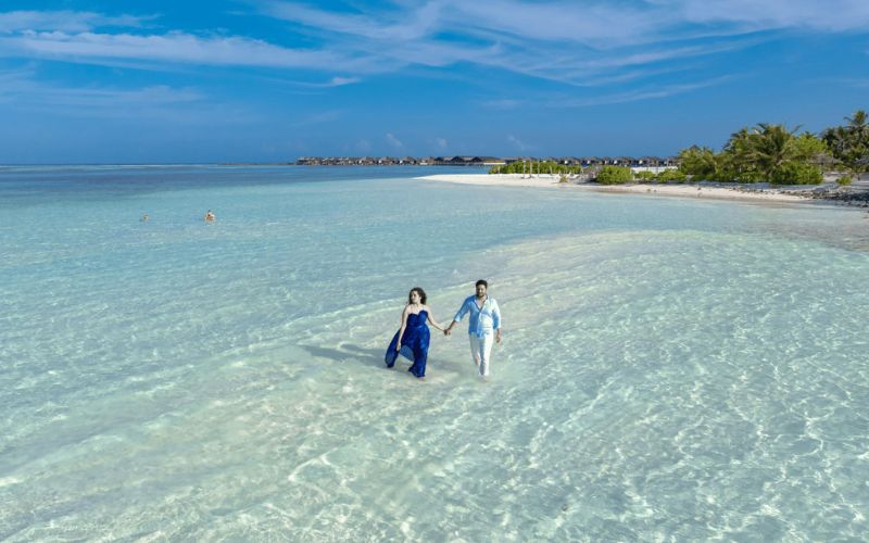 para trzymająca się za ręce, spacerująca w wodzie na Malediwach