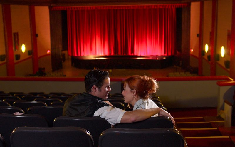 Zdjęcie przedstawia szczęśliwą, obejmującą się parę w teatrze