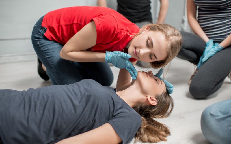 Zdjęcie przedstawia kobietę, która ocenia oddech poszkodowanej
