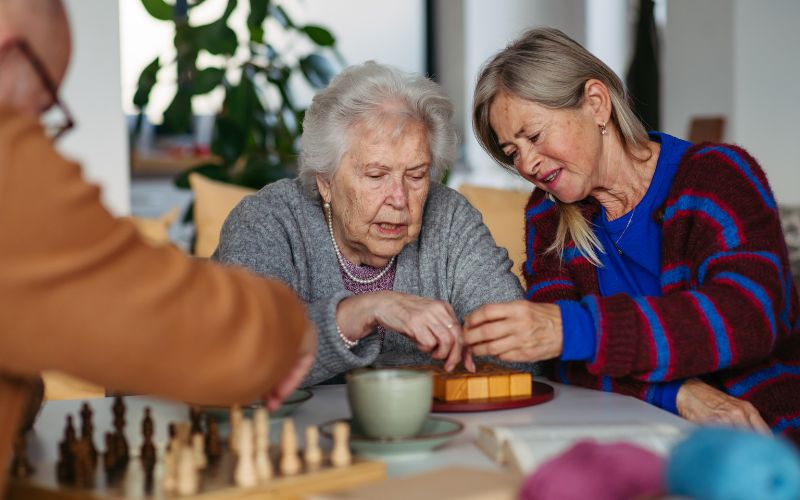 Zdjęcie przedstawia dwie kobiety na emeryturze, które grają w szachy