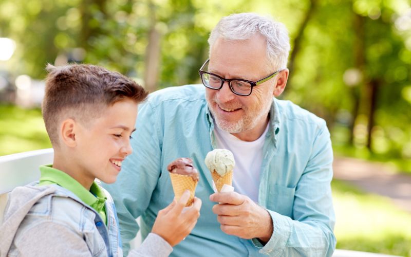 Zdjęcie przedstawia mężczyznę i chłopczyka, którzy jedzą lody