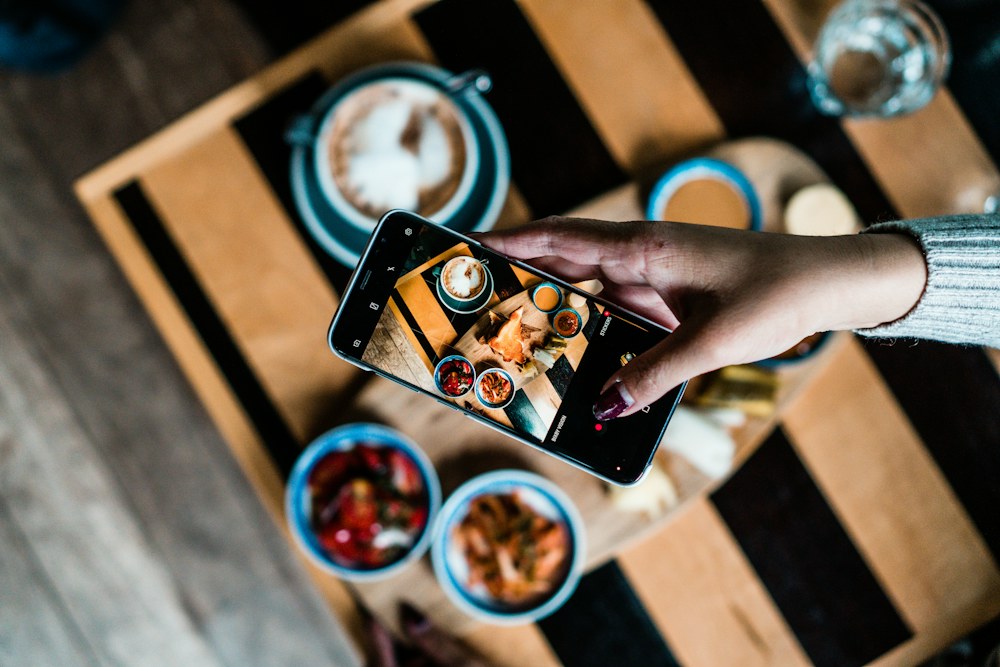 Telefon kadrujący potrawy i kawę na stoliku w restauracji