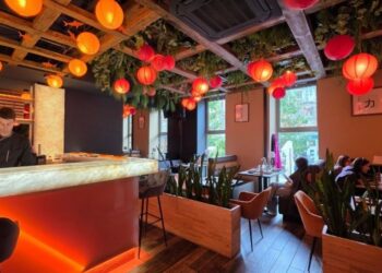 Wnętrze restauracji SAME sushi & robata w Szczecinie z oświetlonymi stolikami oraz widokiem na Sushimastera