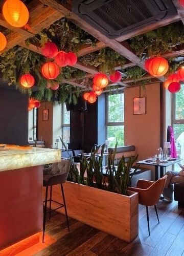 Wnętrze restauracji SAME sushi & robata w Szczecinie z oświetlonymi stolikami oraz widokiem na Sushimastera