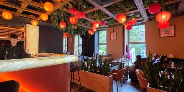 Wnętrze restauracji SAME sushi & robata w Szczecinie z oświetlonymi stolikami oraz widokiem na Sushimastera